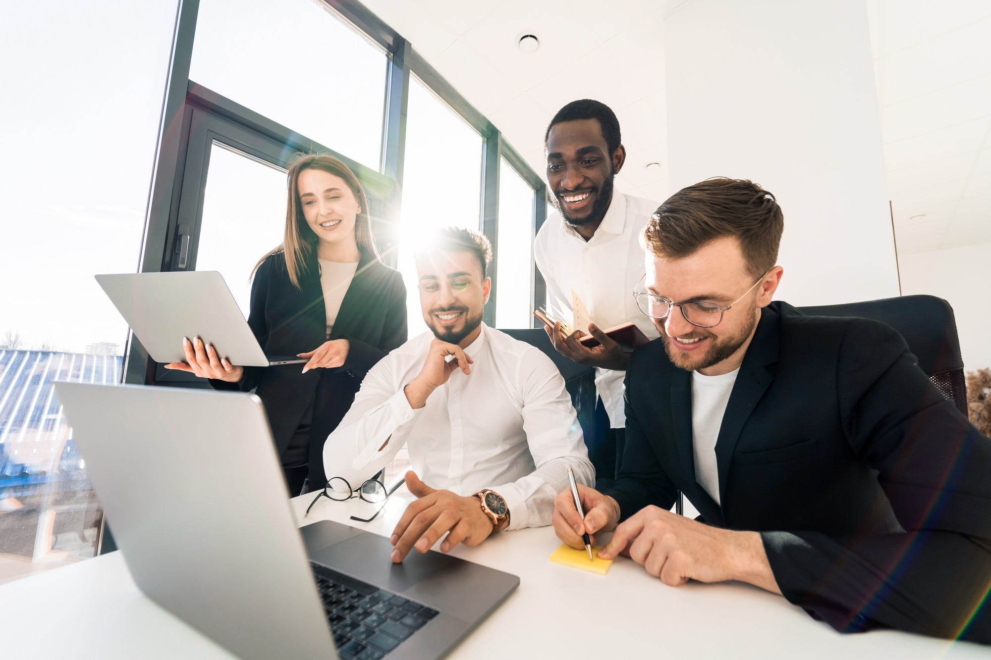 Company employees work together on a laptop